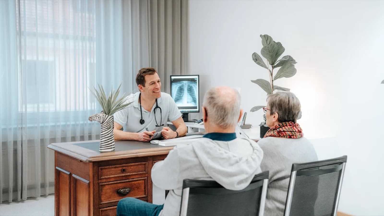 Arzt im Gespräch mit zwei Patienten in der Sprechstunde